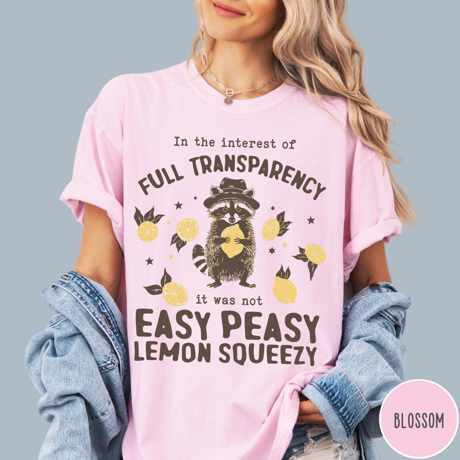 Comfort Colors tee in Blossom featuring graphic illustration of a raccoon wearing a hat holding a lemon