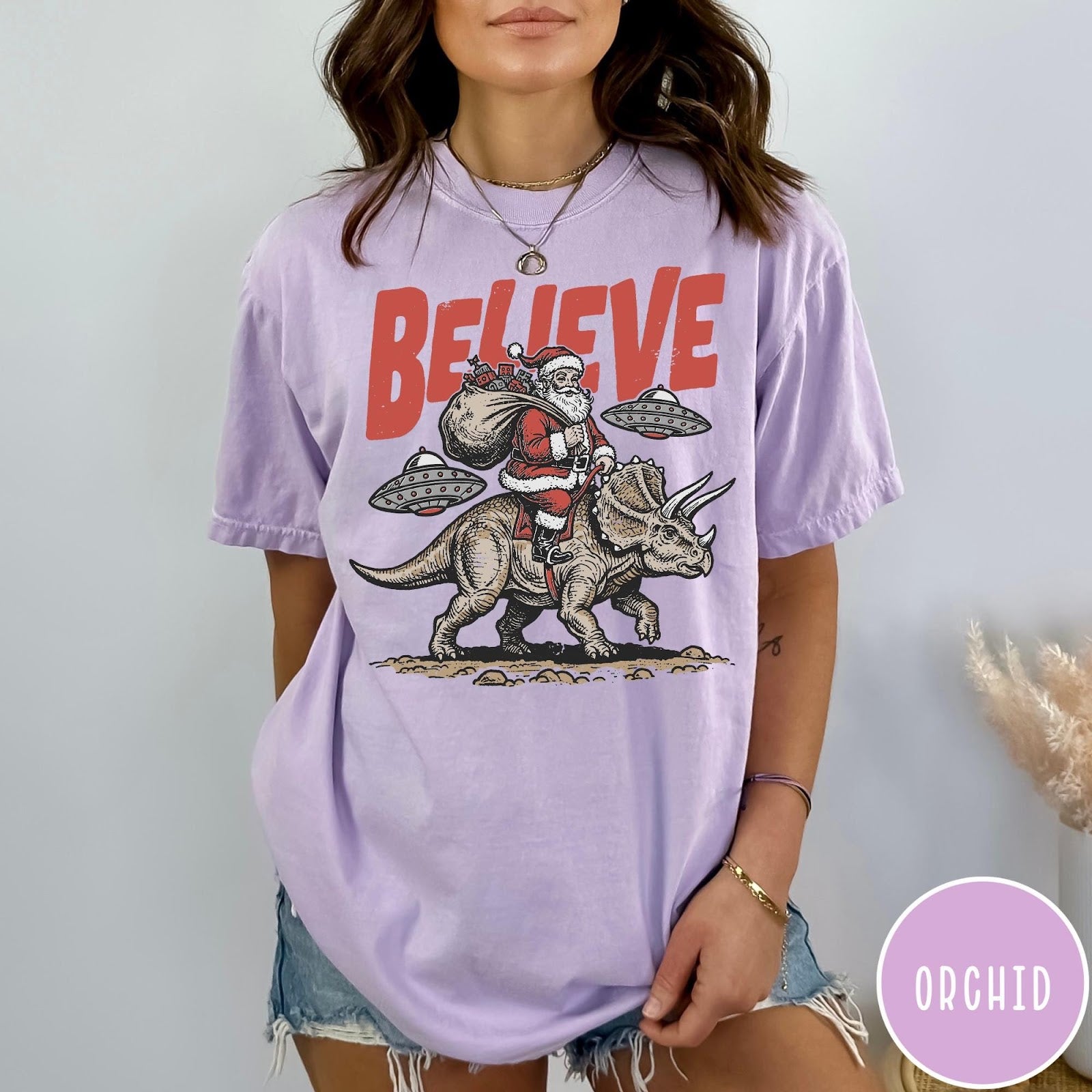 Comfort Colors tee in Orchid featuring vintage style graphic of Santa riding a dinosaur with flying saucers