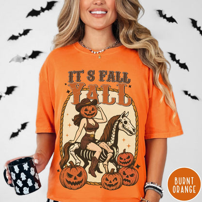 Comfort Colors tee in Burnt Orange featuring western graphic of a pumpkin cowgirl riding a skeleton horse with pumpkins