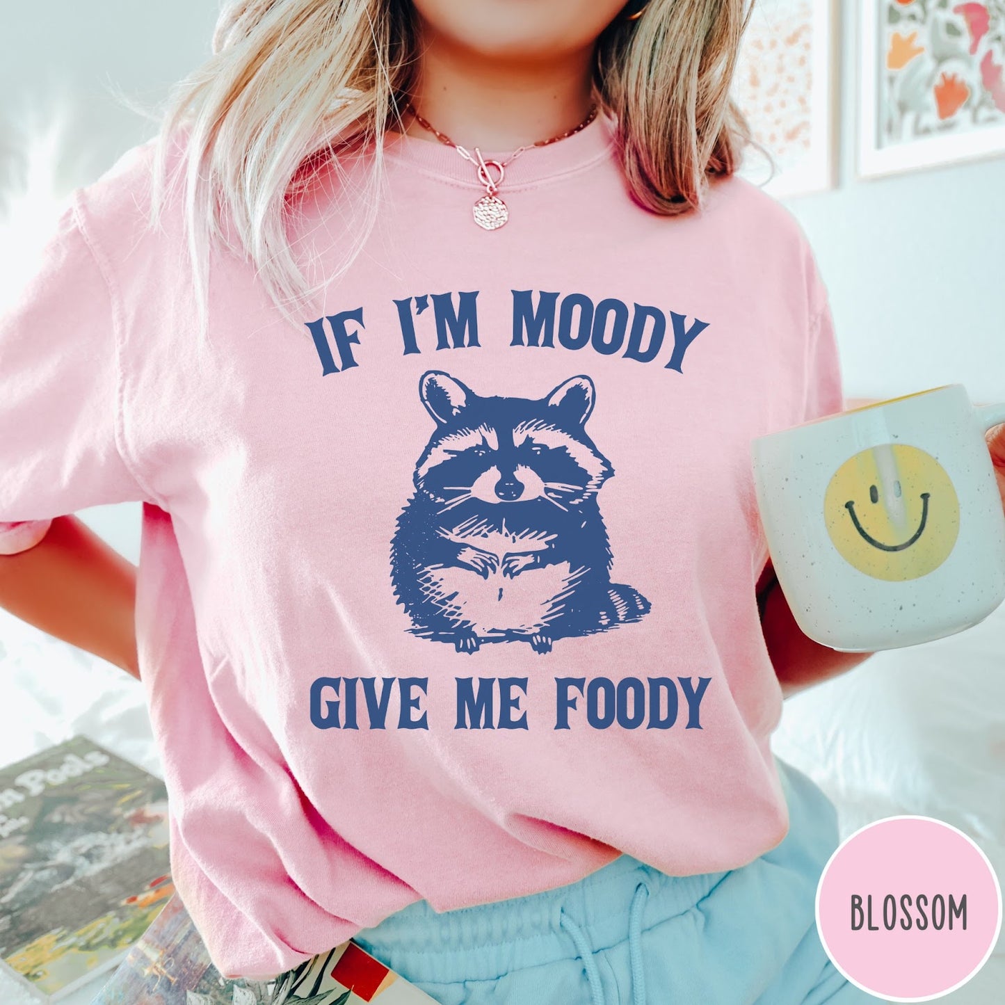 Comfort Colors tee in Blossom featuring vintage style graphic of a raccoon with text If I'm Moody Give Me Foody