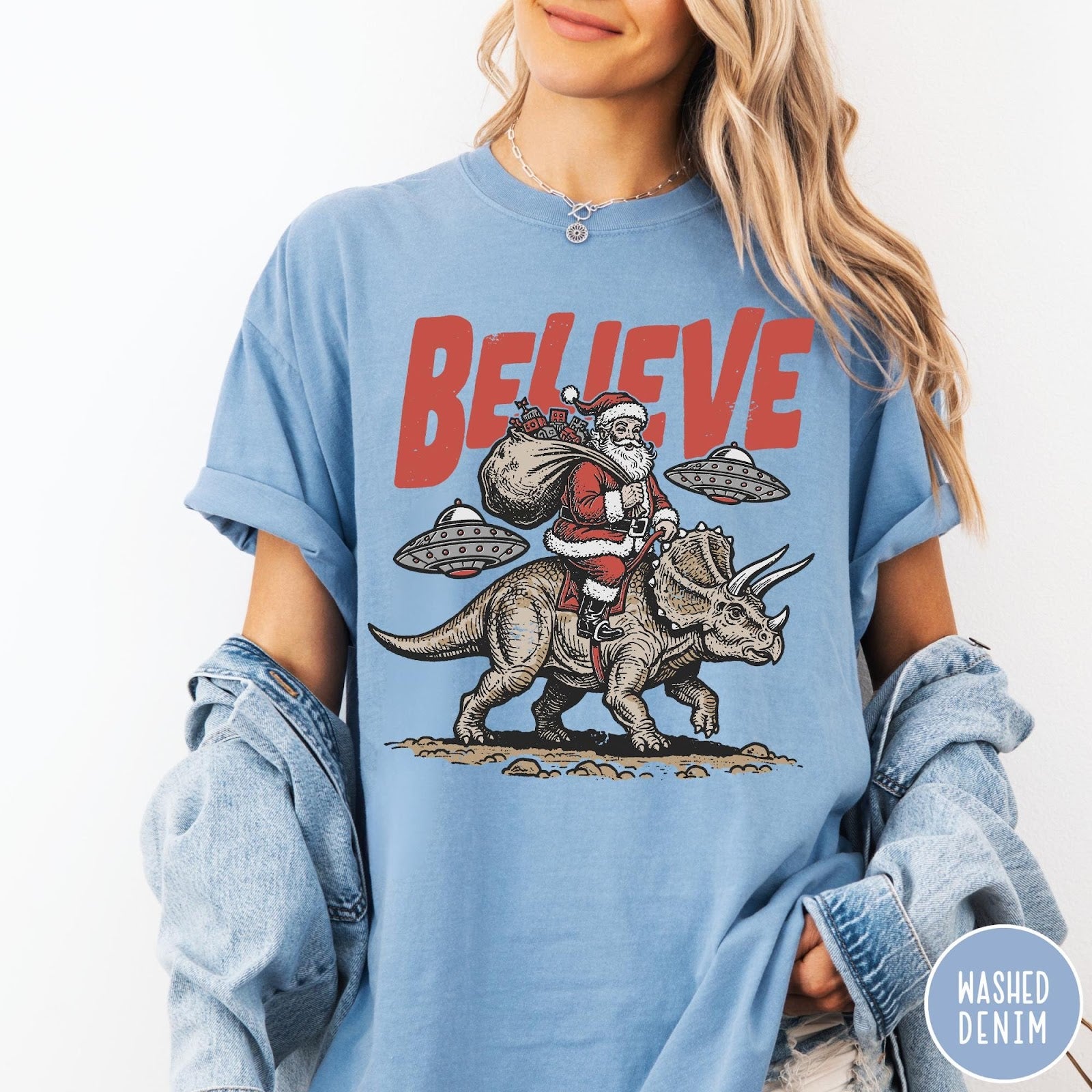 Comfort Colors tee in Washed Denim featuring graphic illustration of Santa riding a dinosaur with flying saucers above