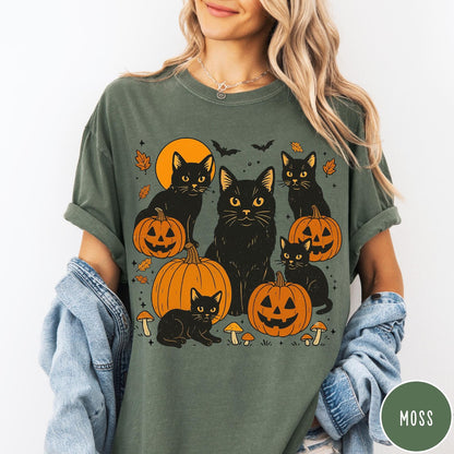 Comfort Colors tee in Moss featuring Halloween style graphic with black cats, pumpkins, bats, and fall leaves