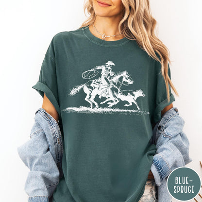 Comfort Colors tee in Blue Spruce featuring western style graphic of a cowboy roping a calf on horseback