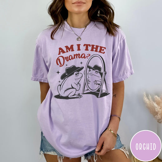 Comfort Colors tee in Orchid featuring whimsical frog graphic with a cowboy hat looking into a mirror