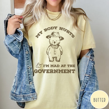 Comfort Colors tee in Butter featuring line art style bear wearing a hat and button-up shirt graphic