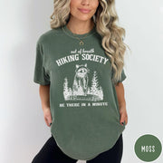Comfort Colors tee in Moss featuring outdoor style graphic of a raccoon standing in the forest