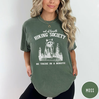 Comfort Colors tee in Moss featuring outdoor style graphic of a raccoon standing in the forest