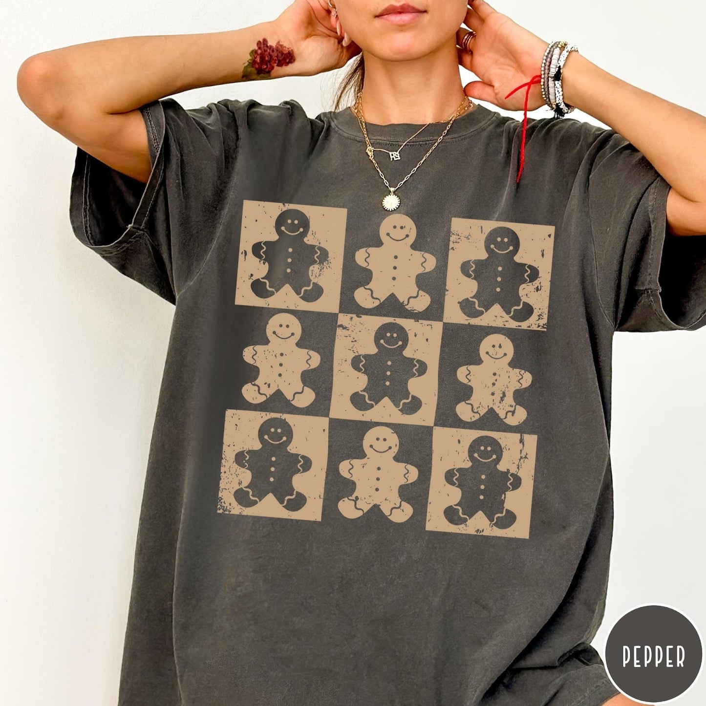 Comfort Colors tee in Pepper featuring a grid style graphic of nine distressed gingerbread cookie character illustrations.