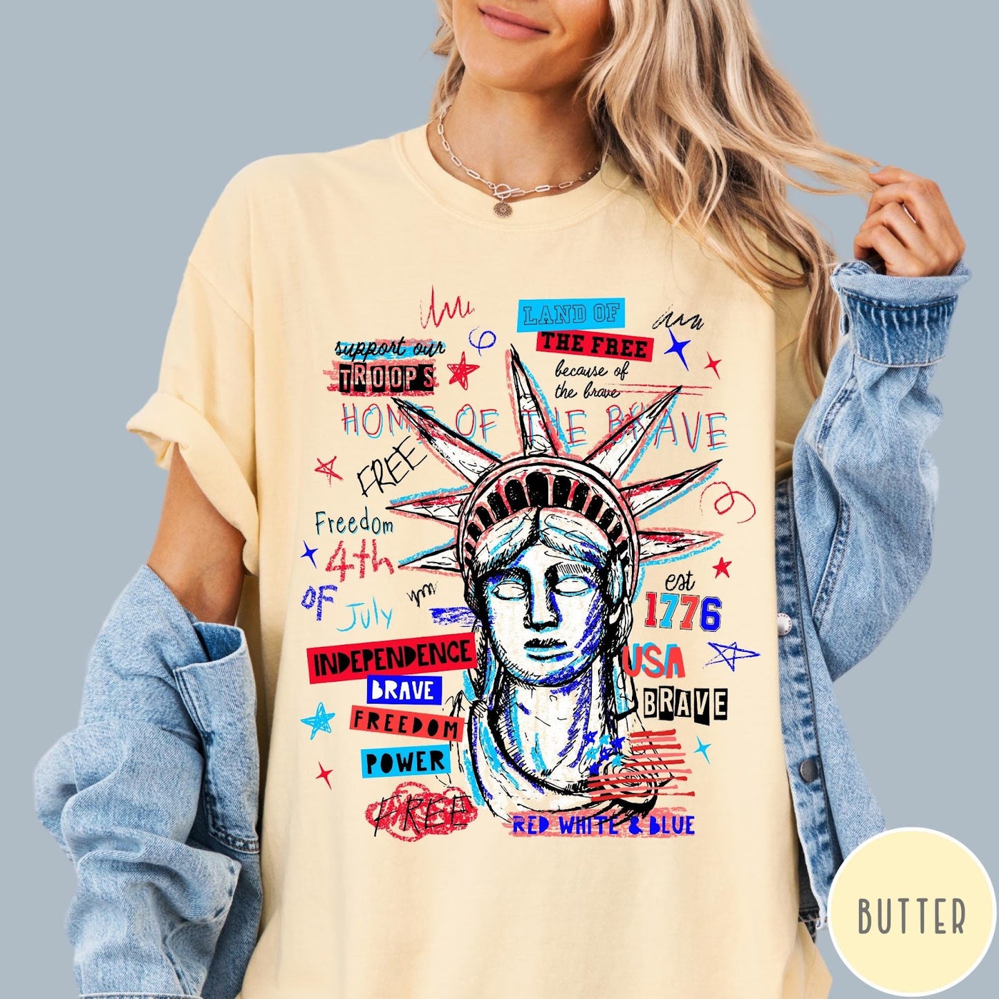 Comfort Colors tee in Butter featuring grunge style Statue of Liberty graphic with patriotic red and blue text