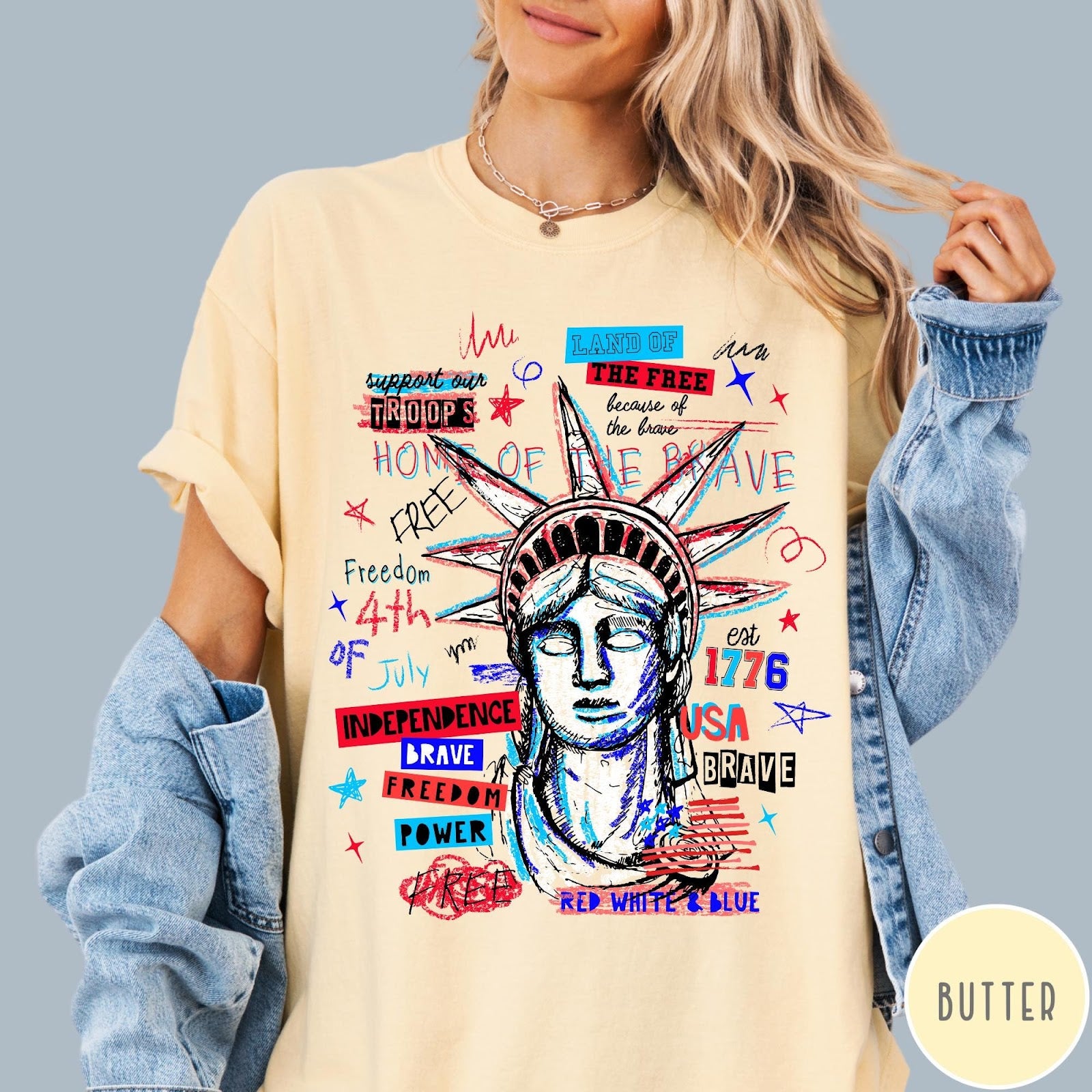 Comfort Colors tee in Butter featuring grunge style Statue of Liberty graphic with patriotic red and blue text
