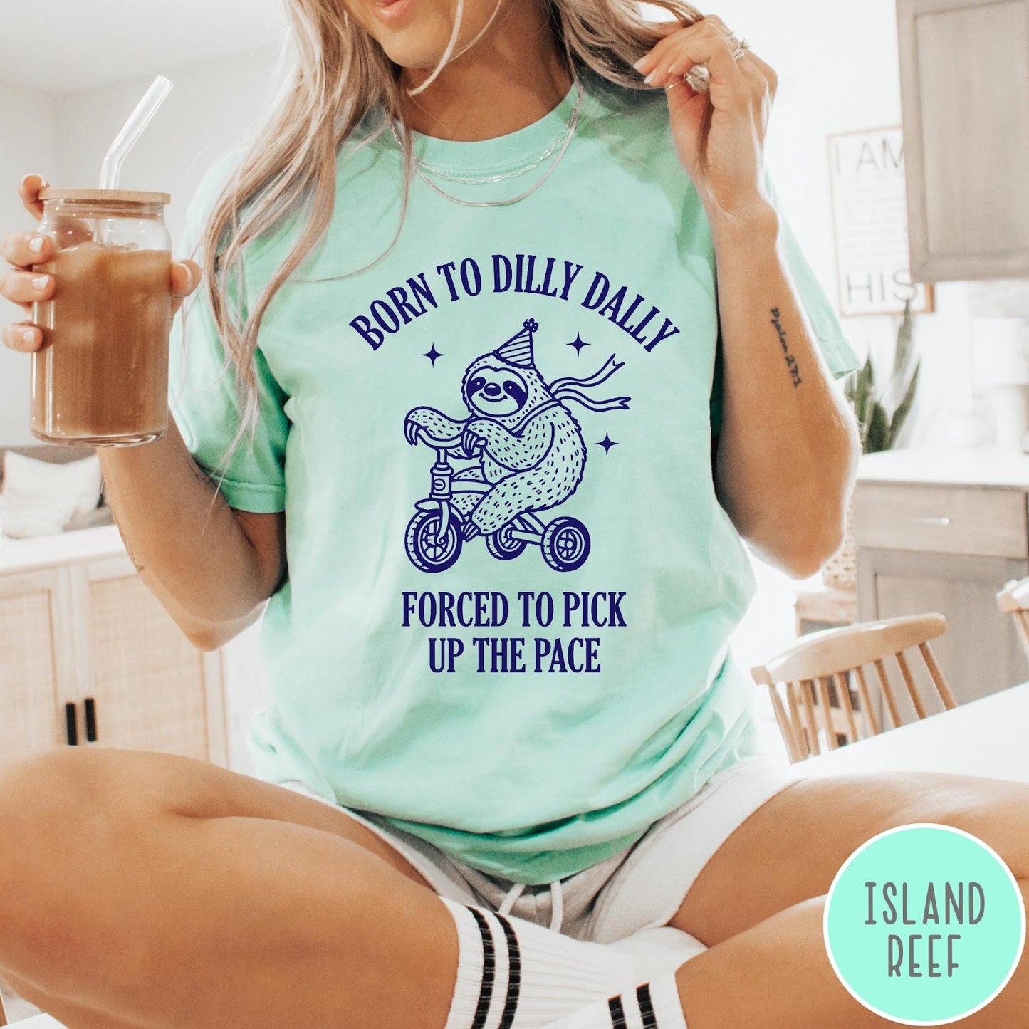 Comfort Colors tee in Island Reef featuring cute sloth on a tricycle graphic with Born to Dilly Dally text