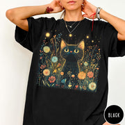 Comfort Colors tee in Black featuring artistic graphic of a black cat sitting in a flower field