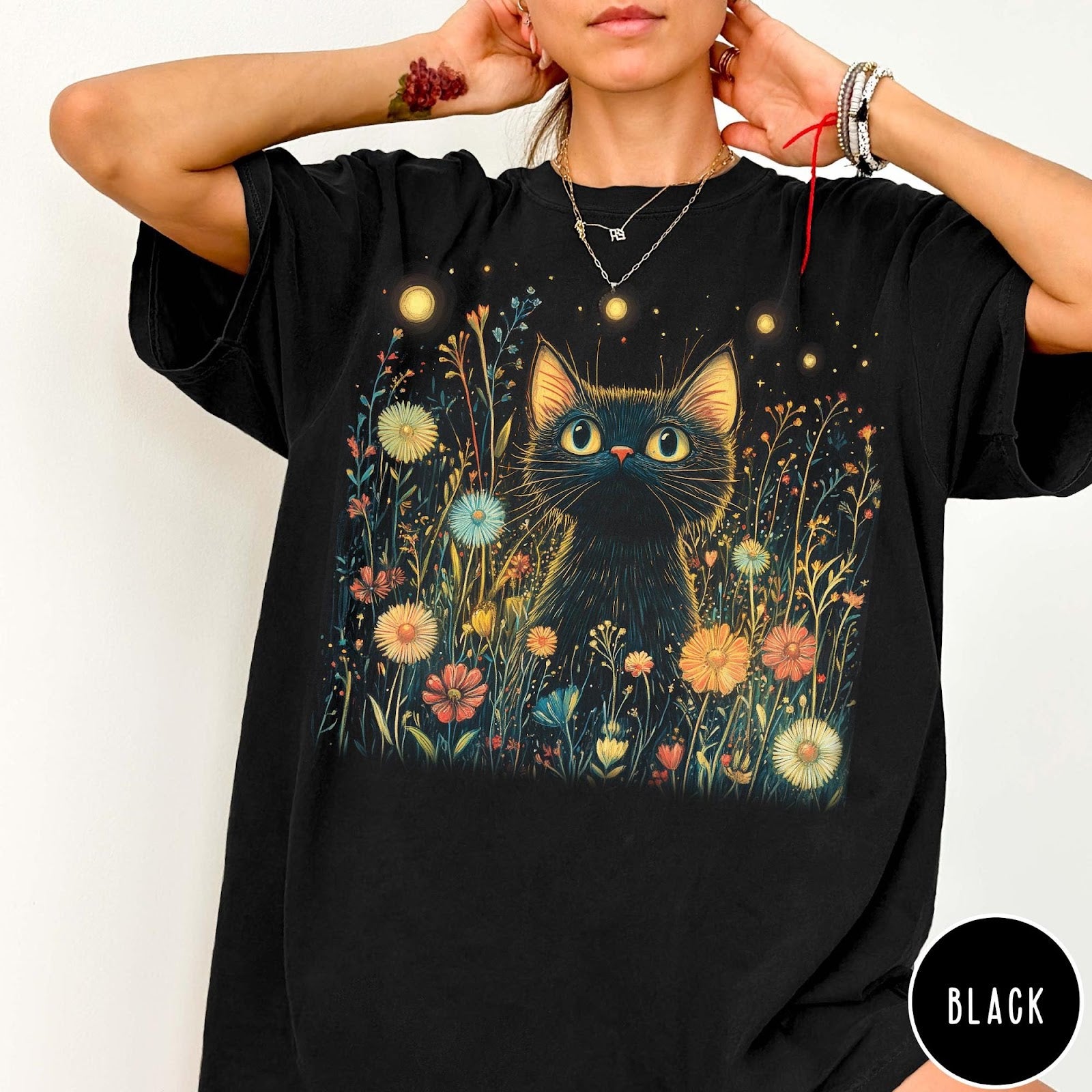 Comfort Colors tee in Black featuring artistic graphic of a black cat sitting in a flower field