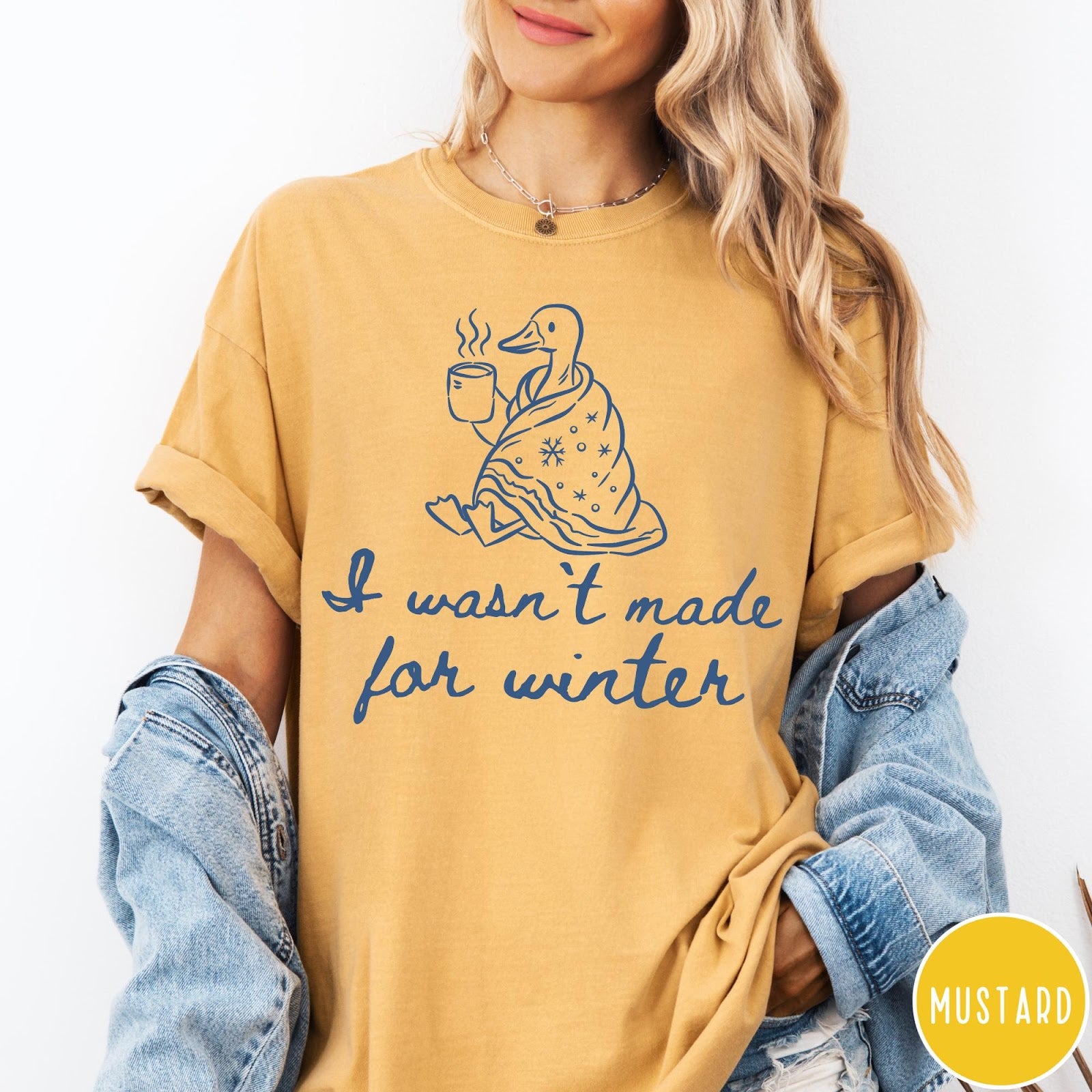 Comfort Colors tee in Mustard featuring line art graphic of a duck wrapped in a blanket drinking coffee