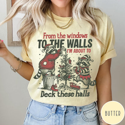 Comfort Colors tee in Butter featuring festive graphic of two raccoons decorating a Christmas tree with holiday text