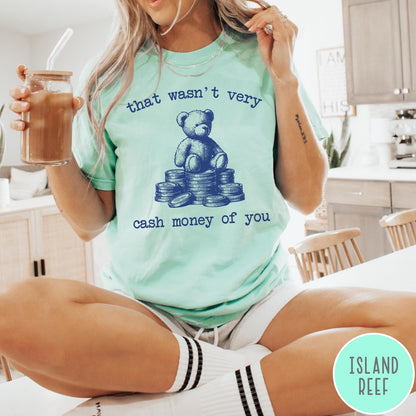 Comfort Colors tee in Island Reef featuring graphic style teddy bear sitting on a stack of coins