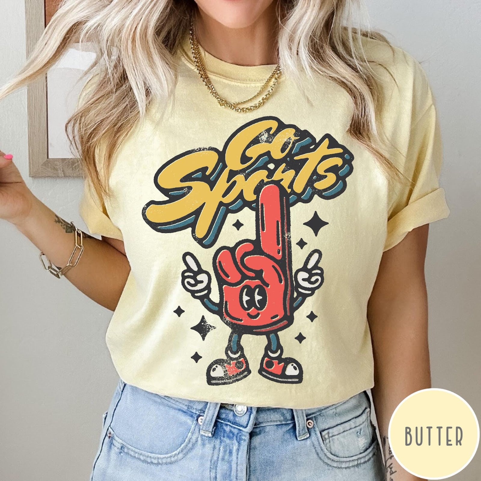 Comfort Colors tee in Butter featuring retro mascot design with a red foam finger and Go Sports text