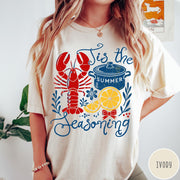 Comfort Colors tee in Ivory featuring lobster boil graphic with a lobster, cooking pot, and lemon slices.