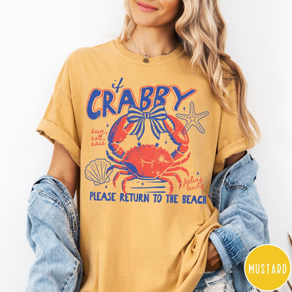 Comfort Colors tee in Mustard featuring beachy crab graphic with bow, starfish, seashell, and coastal text