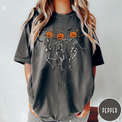 Comfort Colors tee in Pepper featuring dancing skeleton graphic with jack-o'-lantern heads and small orange stars