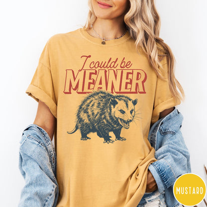 Comfort Colors tee in Mustard featuring a graphic design of a hissing opossum with text I could be meaner