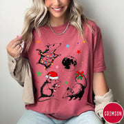 Comfort Colors tee in Crimson featuring holiday possum graphic with Christmas lights, candy cane, and moon.