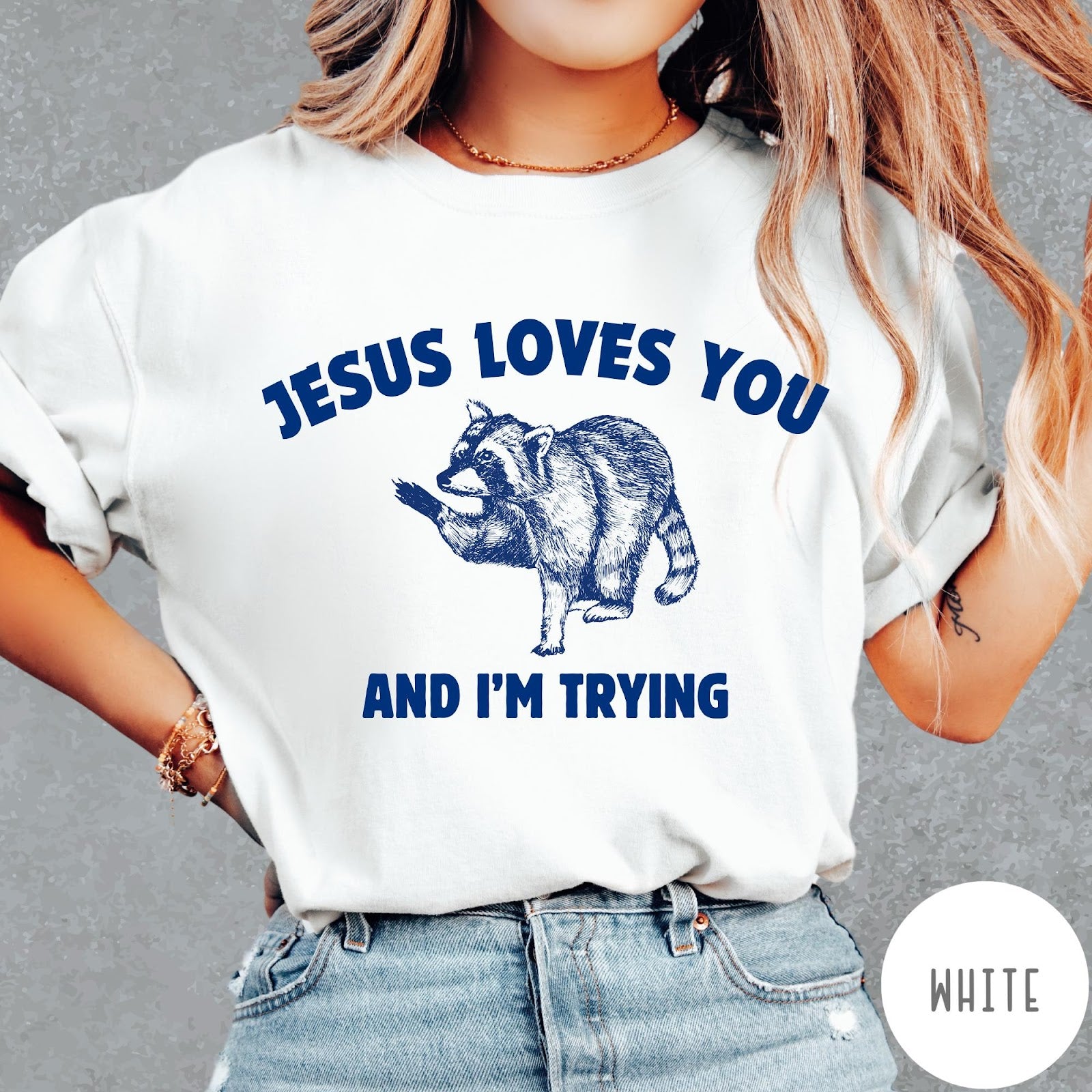 Comfort Colors tee in White featuring graphic style raccoon illustration with text Jesus Loves You And I'm Trying