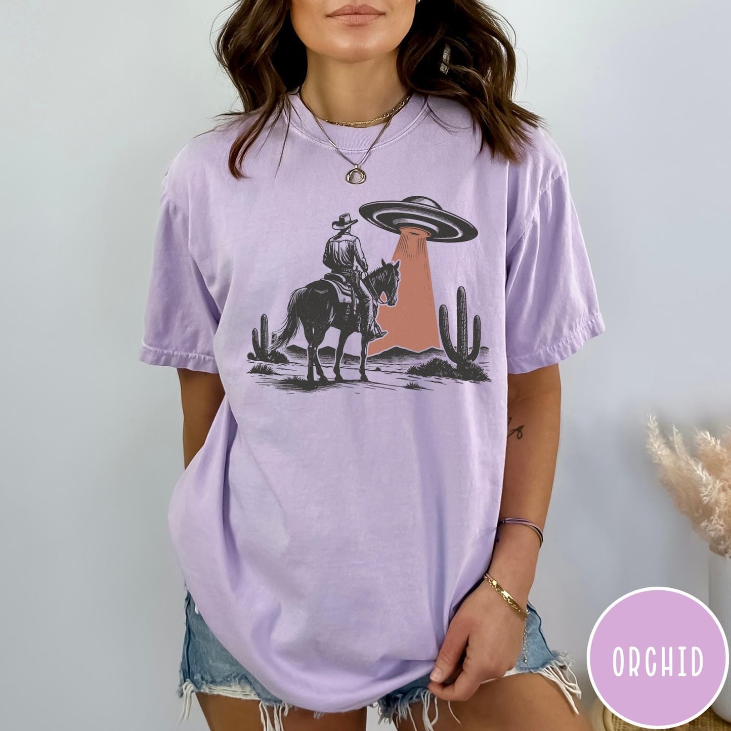 Comfort Colors tee in Orchid featuring western style graphic of a cowboy on horseback under a UFO