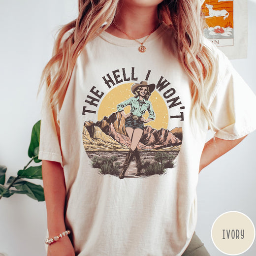 Comfort Colors tee in Ivory featuring western graphic design of a cowgirl standing in front of mountains.