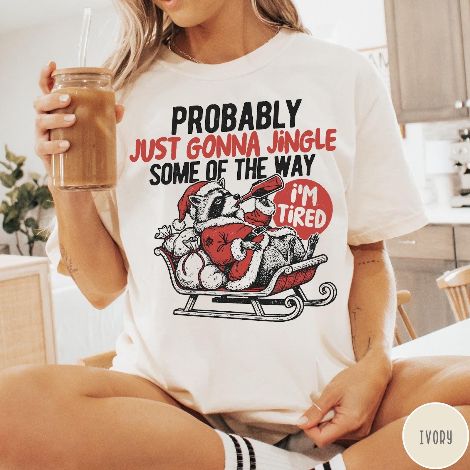 Comfort Colors tee in Ivory featuring festive raccoon graphic in a sleigh with holiday text design