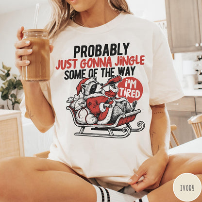 Comfort Colors tee in Ivory featuring festive raccoon graphic in a sleigh with holiday text design