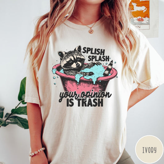 Comfort Colors tee in Ivory featuring illustrative graphic of a raccoon sitting in a pink bathtub