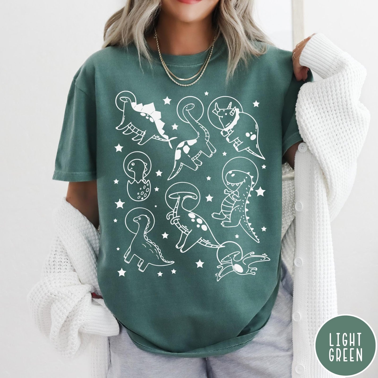 Comfort Colors tee in Light Green featuring line art graphic of various dinosaurs wearing astronaut helmets in space