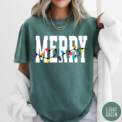 Comfort Colors tee in Light Green featuring holiday style graphic with white Merry text and colorful Christmas lights