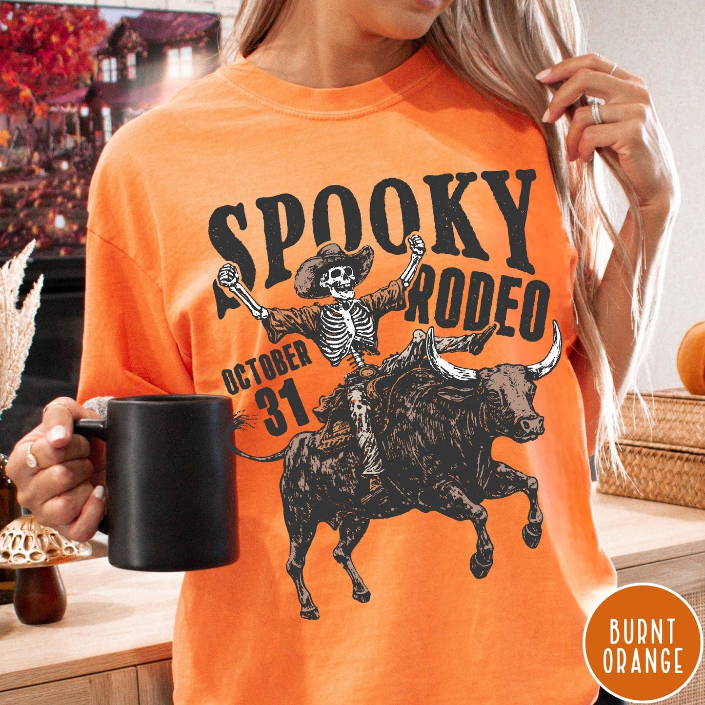 Comfort Colors tee in Burnt Orange featuring western style graphic of a skeleton cowboy riding a bucking bull