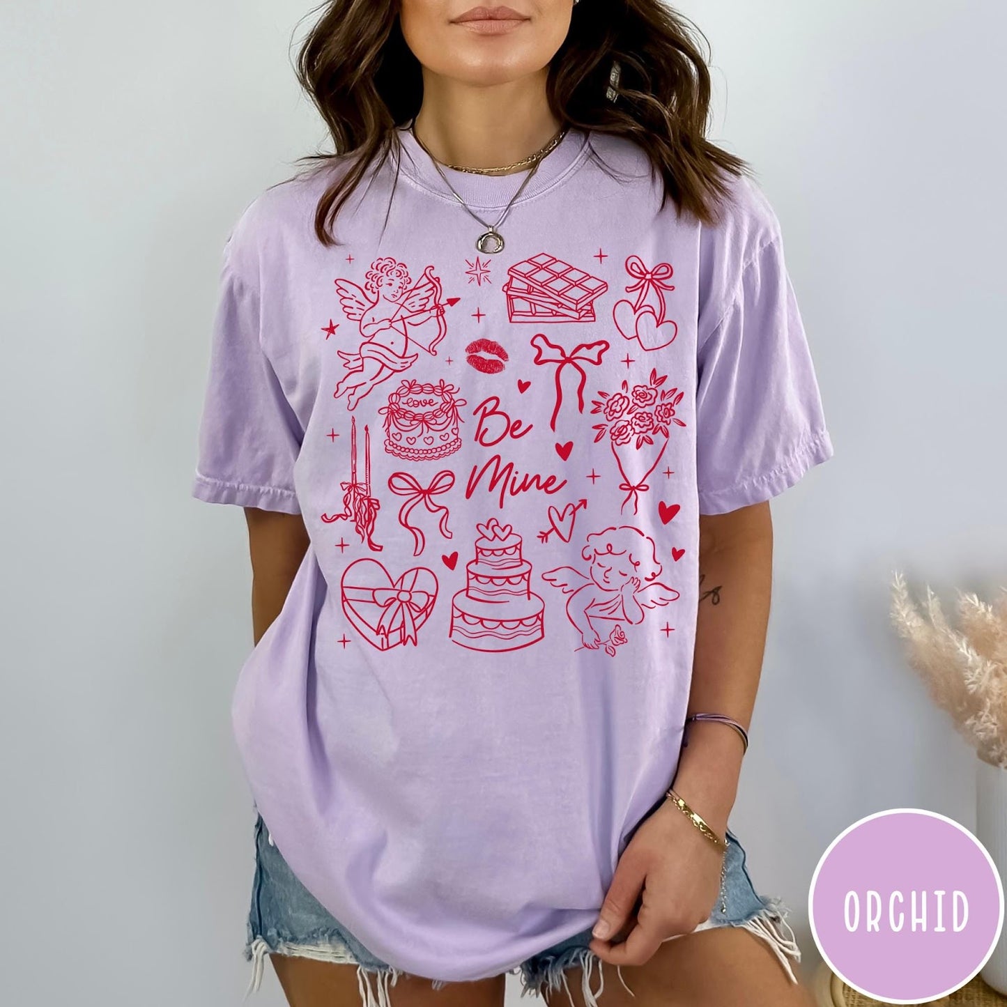 Comfort Colors tee in Orchid featuring Valentine's Day collage design with cupid, cake, flowers, and chocolate graphics