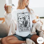 Comfort Colors tee in White featuring tarot card style graphic of a skeleton reading a book