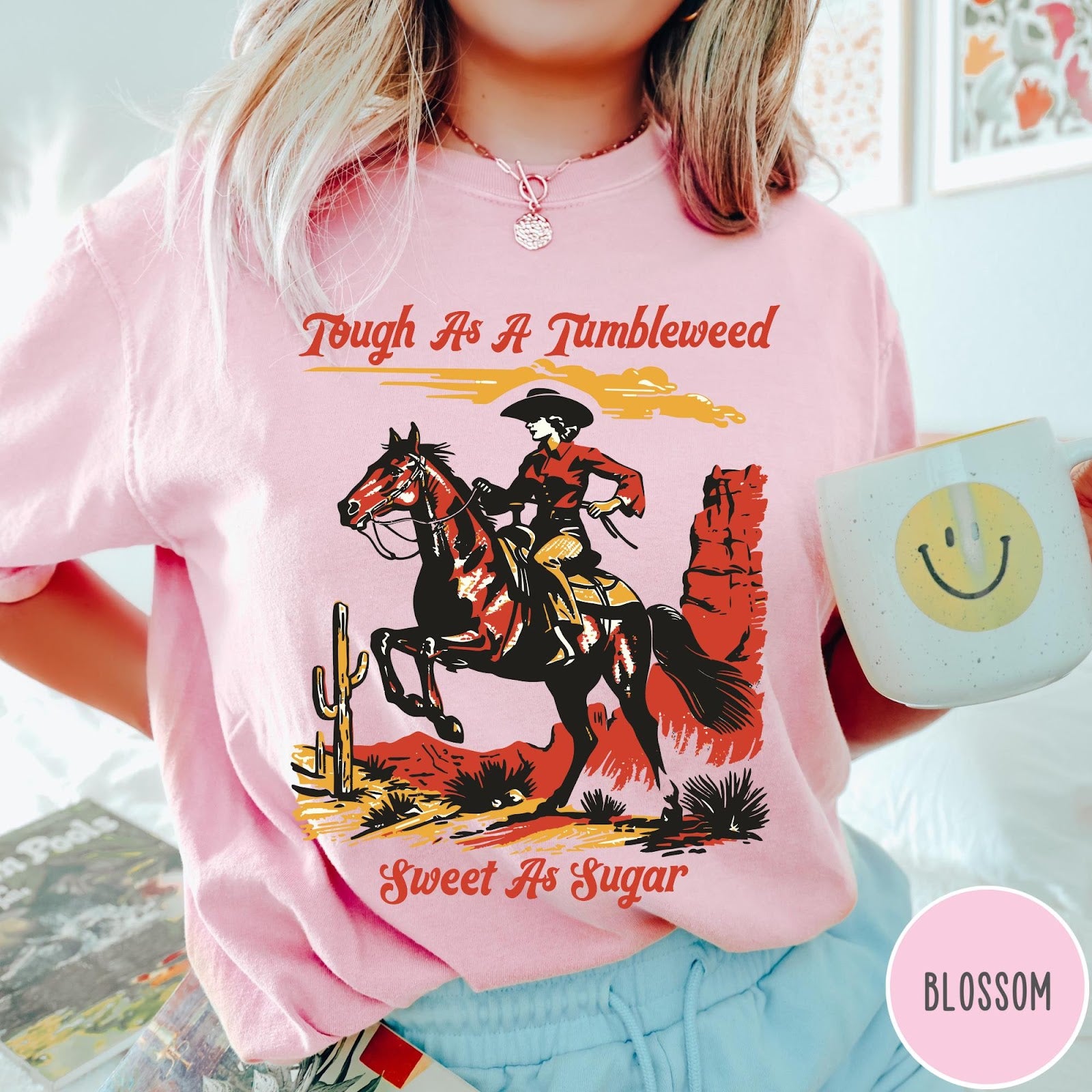 Comfort Colors tee in Blossom featuring western style graphic of a cowgirl riding a horse in desert