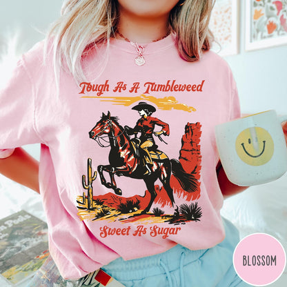 Comfort Colors tee in Blossom featuring western style graphic of a cowgirl riding a horse in desert