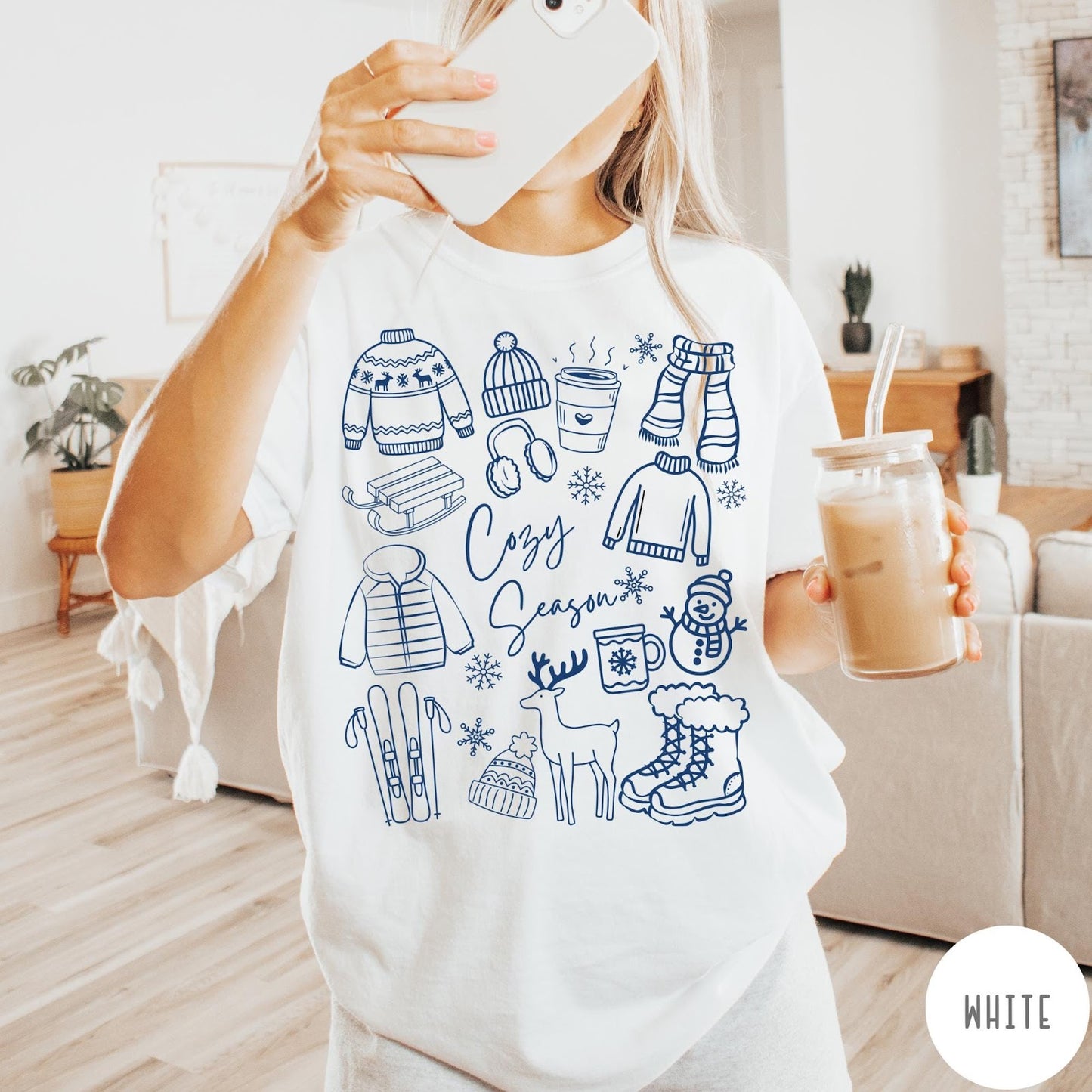 Comfort Colors tee in White featuring winter activities graphic with sweaters, sled, snowman, and seasonal items.