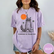 Comfort Colors tee in Orchid featuring vintage style graphic of a raccoon making a peace sign