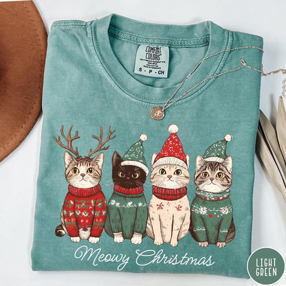 Comfort Colors tee in Light Green featuring holiday graphic of four cats wearing Christmas sweaters and hats