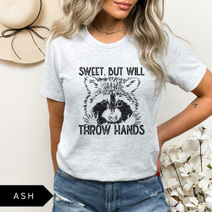 Comfort Colors tee in Ash featuring graphic style raccoon illustration with text Sweet, but will throw hands