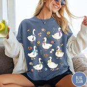 Comfort Colors tee in Blue Jean featuring vintage style graphic of several white geese wearing colorful bows and flowers