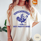 Comfort Colors tee in Ivory featuring western style graphic of a cowgirl riding a large rooster