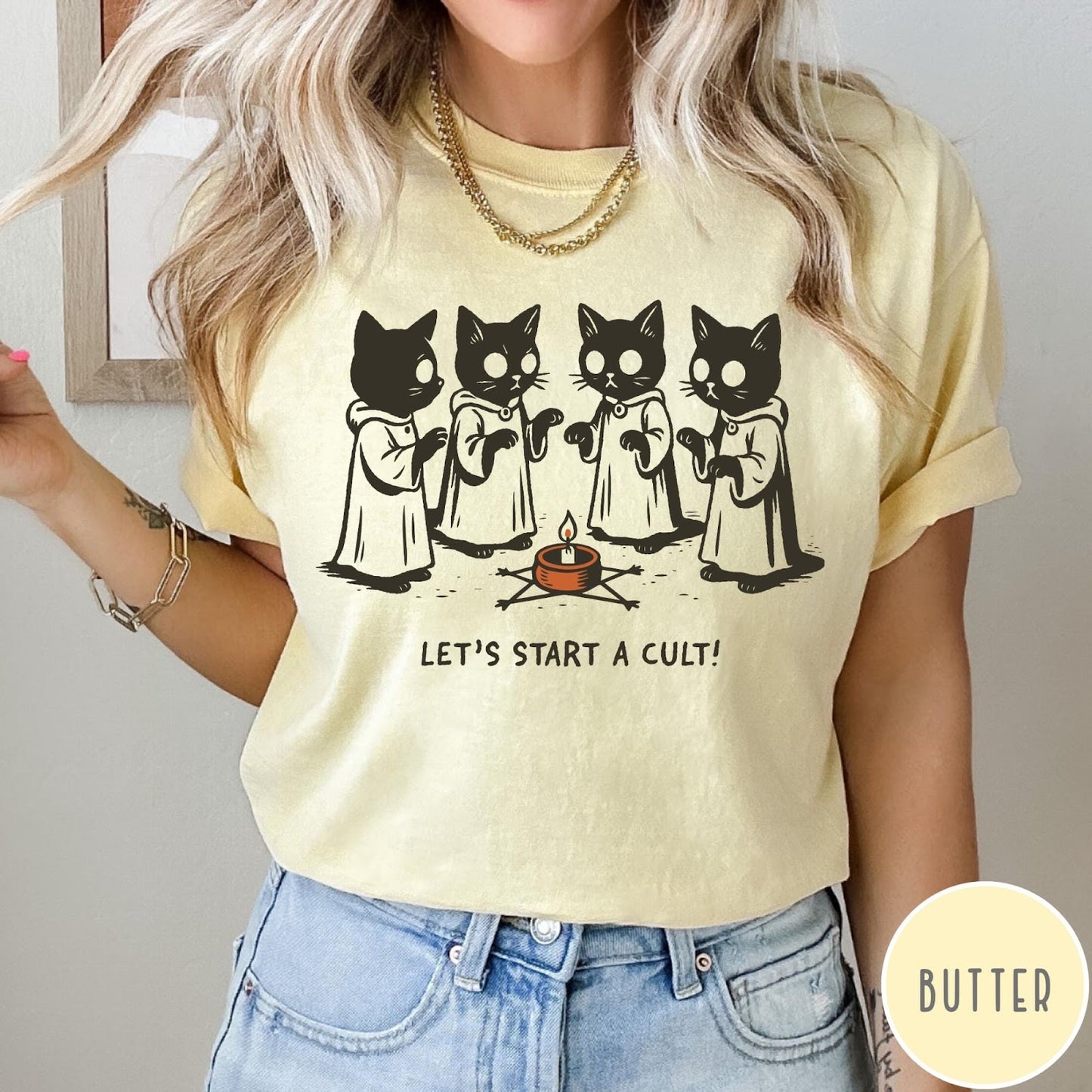 Comfort Colors tee in Butter featuring illustrated style graphic of four cats in robes around a candle