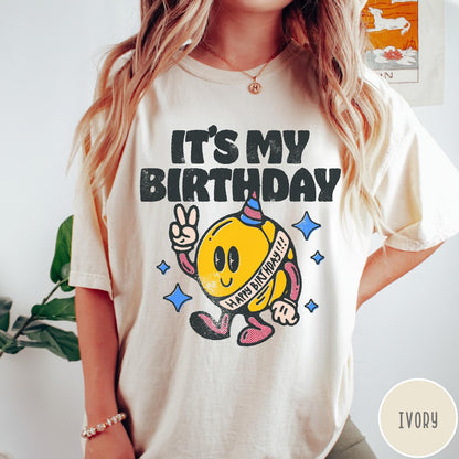 Comfort Colors tee in Ivory featuring retro birthday mascot graphic with peace sign and party hat