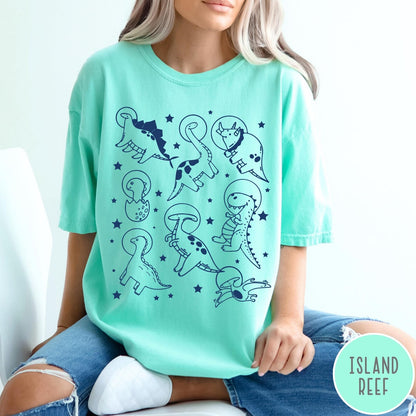 Comfort Colors tee in Island Reef featuring line art graphic of various dinosaurs wearing astronaut helmets in space