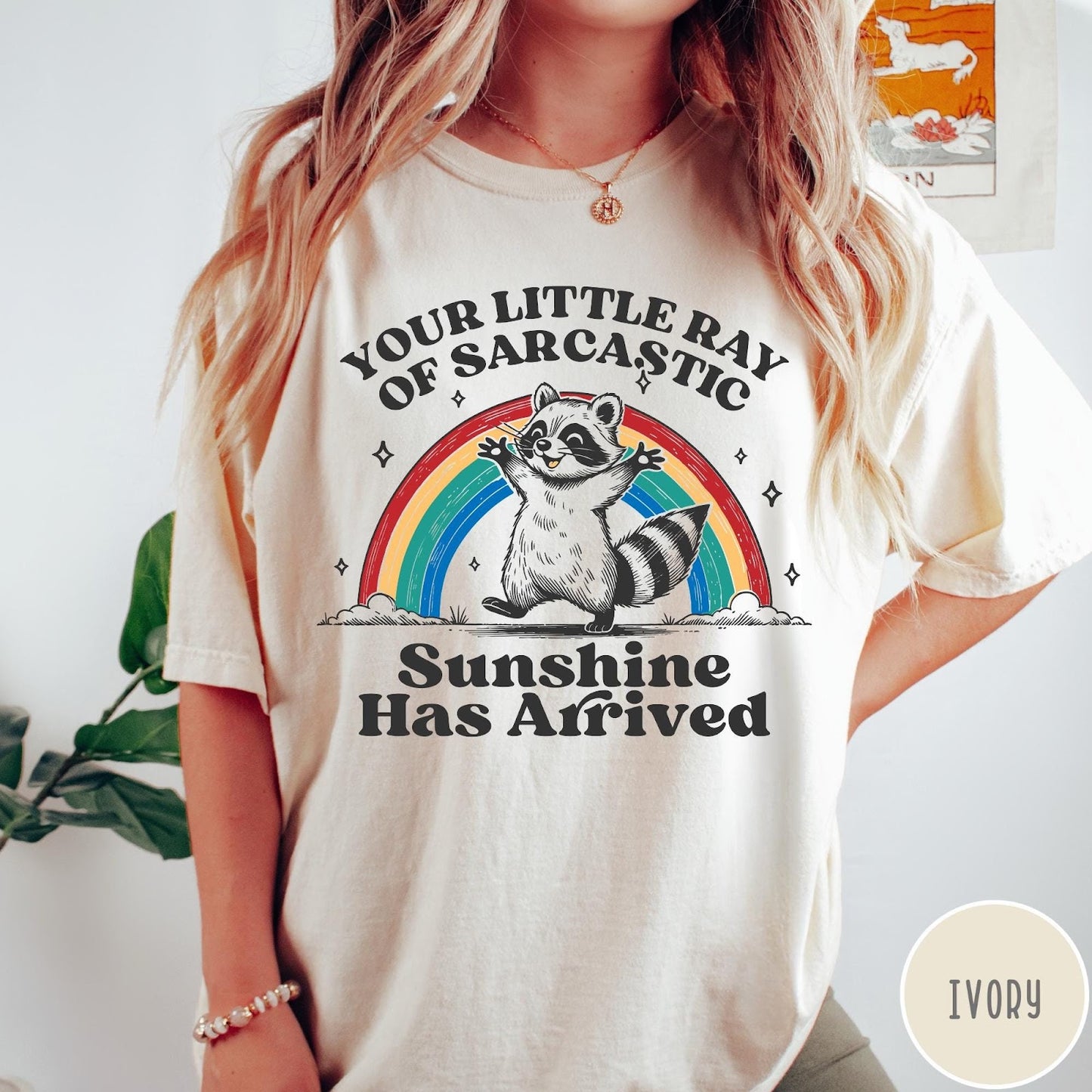 Comfort Colors tee in Ivory featuring vintage style graphic of a happy raccoon standing before a colorful rainbow