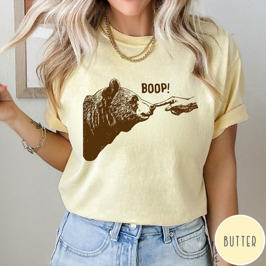 Comfort Colors tee in Butter featuring a brown ink graphic of a human finger booping a bear nose
